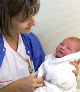 Photo d'une auxiliaire de puériculture qui porte un bébé